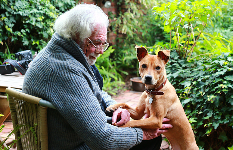 Animal loving bequest supporter with his beloved rescue dog sitting in his garden. Much of the work of The Lost Dogs’ Home is funded by kind bequest gifts from donors.